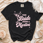 Black t-shirt with pink text "This Bride Needs A Martini" and martini glass graphic.
