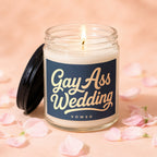 Candle with "Gay Ass Wedding" text, lit flame, black lid, and scattered petals.