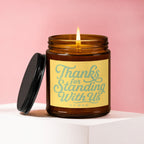 Brown glass candle with lit flame and yellow label that reads "Thanks for Standing With Us VOWED".