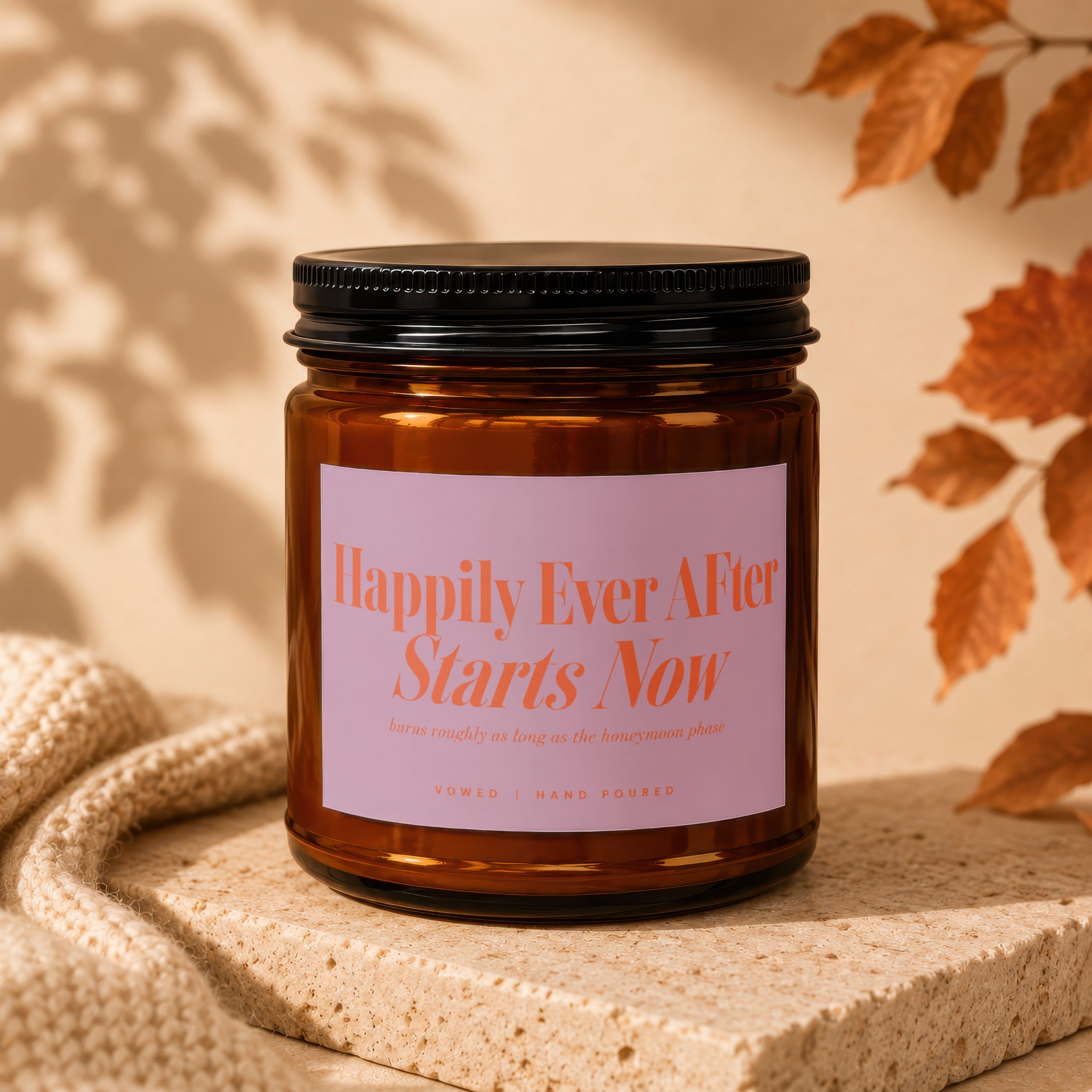 Amber jar candle with pink label reading "Happily Ever After Starts Now."