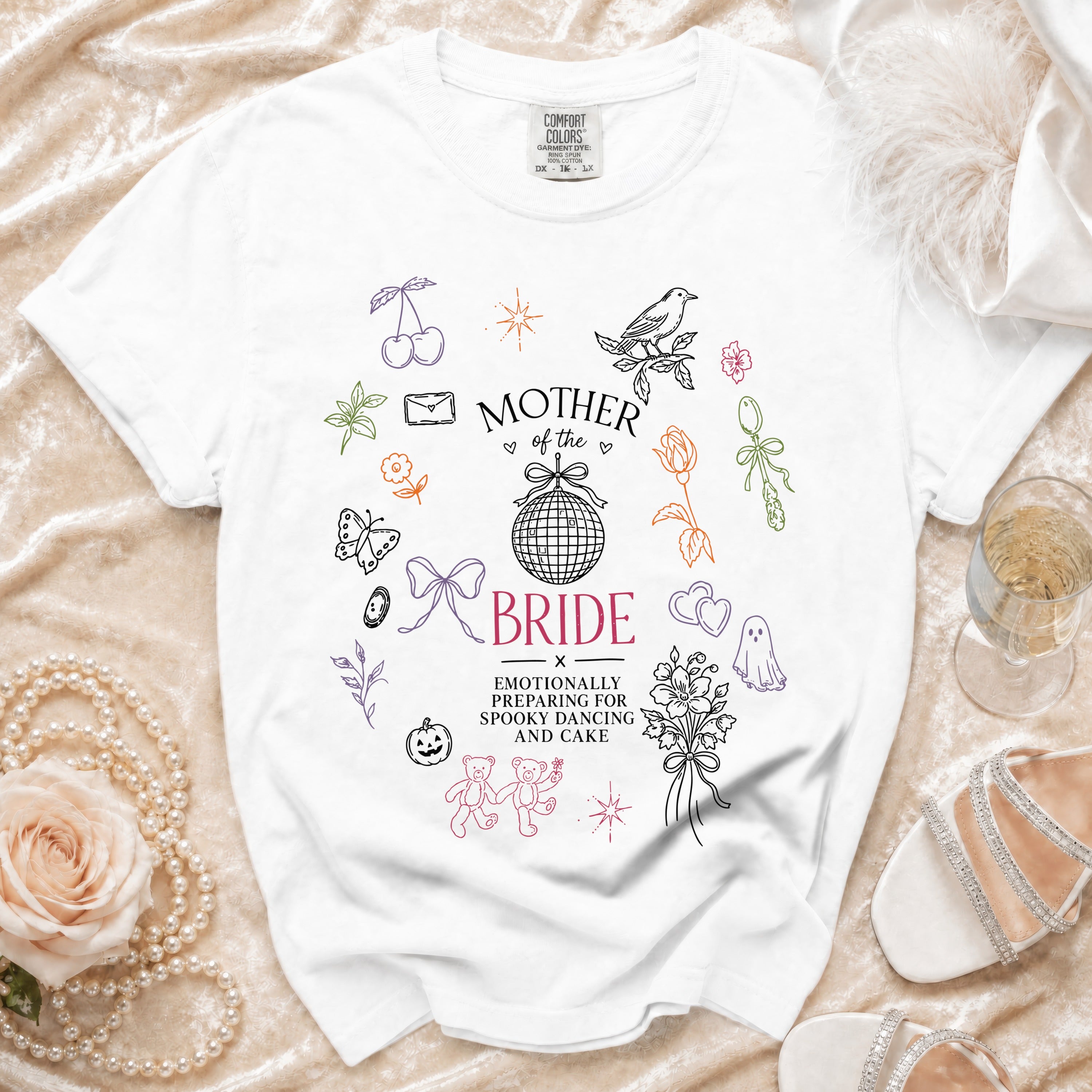 White t-shirt with "Mother of the Bride" and wedding-themed doodles.