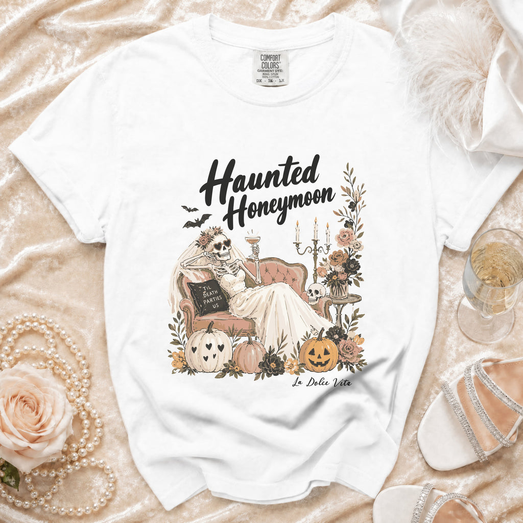 White t-shirt with "Haunted Honeymoon" graphic featuring a skeleton bride and "Til Death Parties Us".