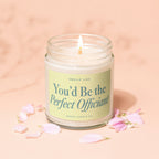 Glass candle with light cream wax and a lit wick, labeled "You'd Be the Perfect Officiant".