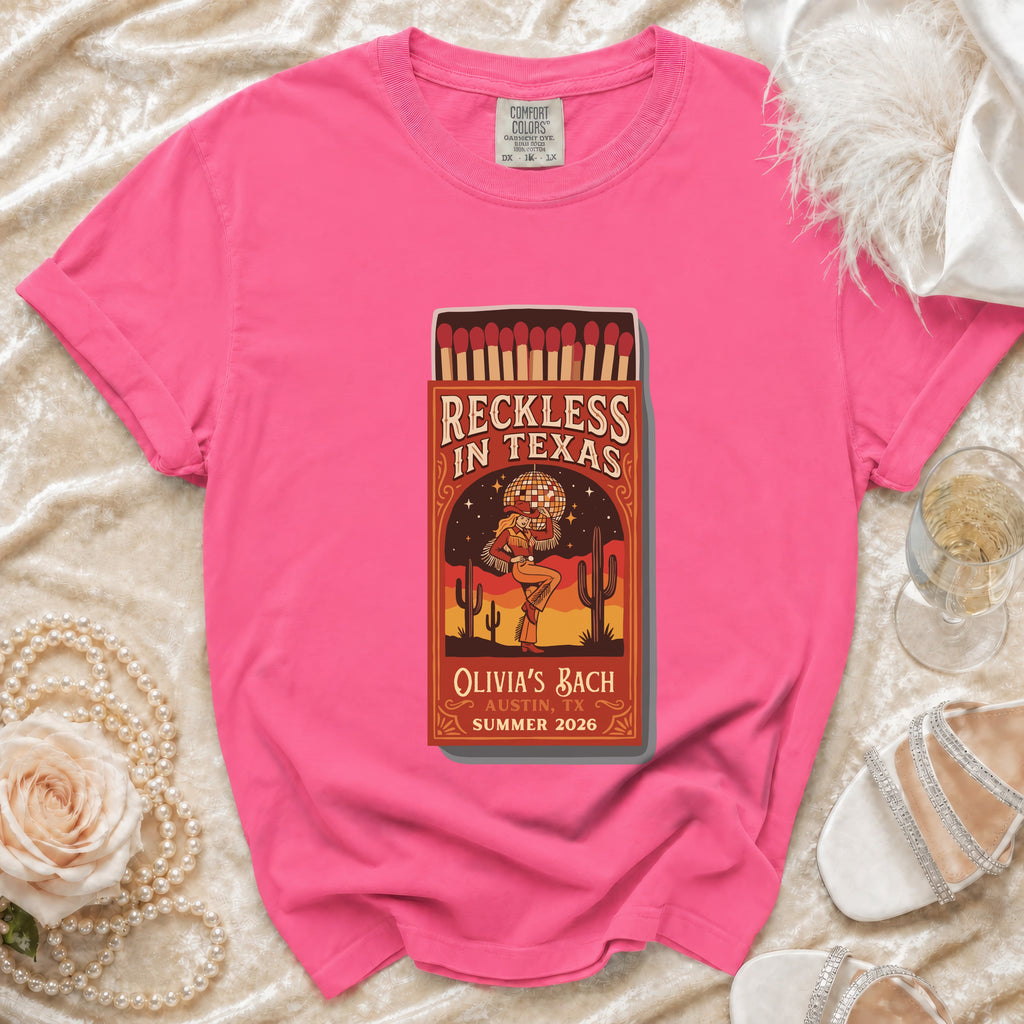 Pink t-shirt with "Reckless in Texas" matchbox graphic and bachelorette details.