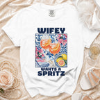 White t-shirt with "WIFEY WANTS A SPRITZ" text and drinks graphic.