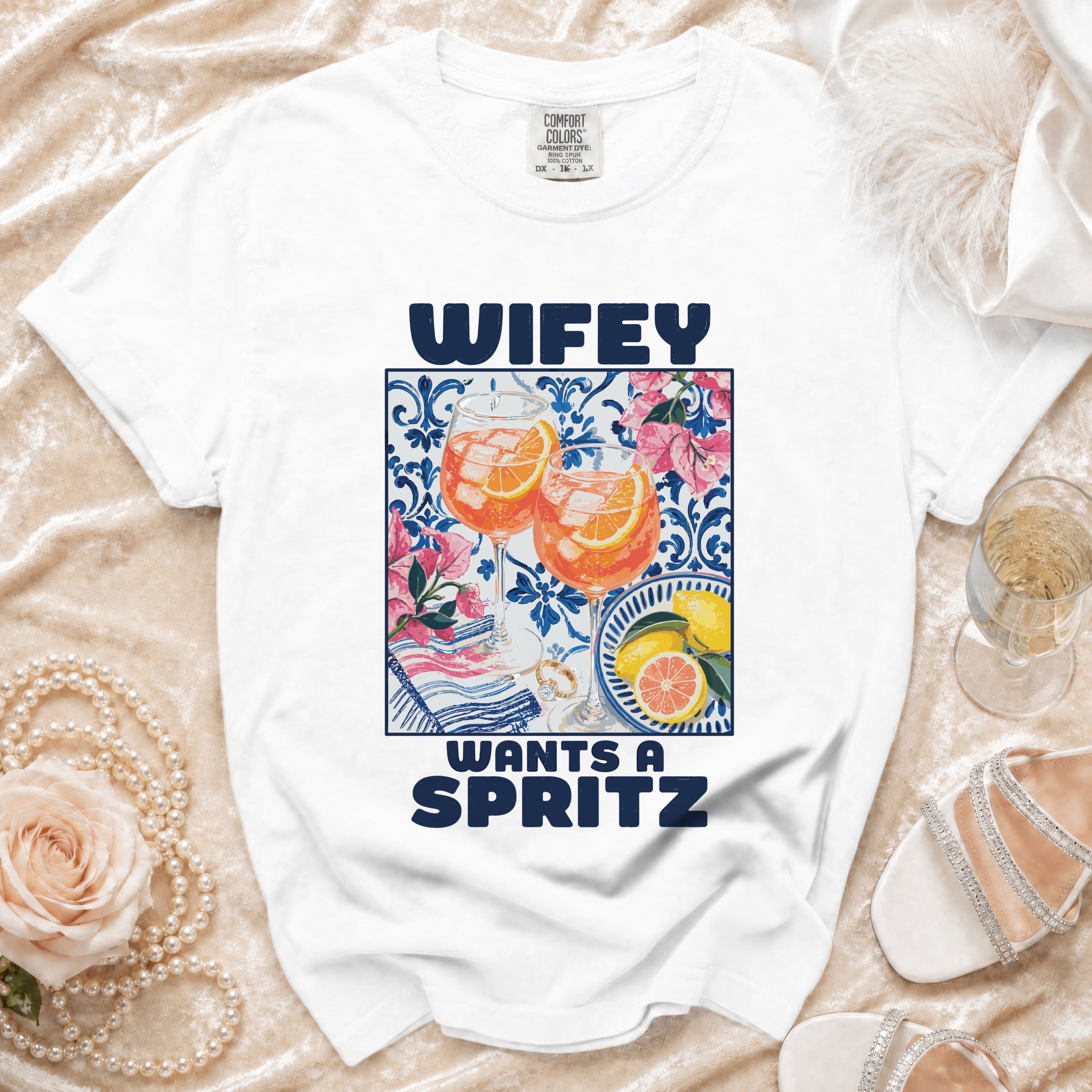 White t-shirt with "WIFEY WANTS A SPRITZ" text and drinks graphic.