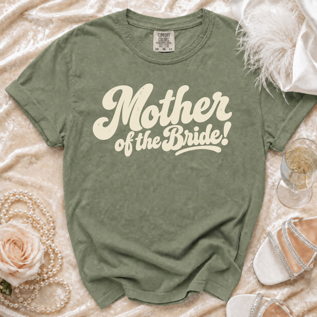 Green t-shirt with cream text "Mother of the Bride!" on textured fabric.