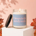Candle with "Cheers to the newlyweds" and "VOWED" on a blue label.