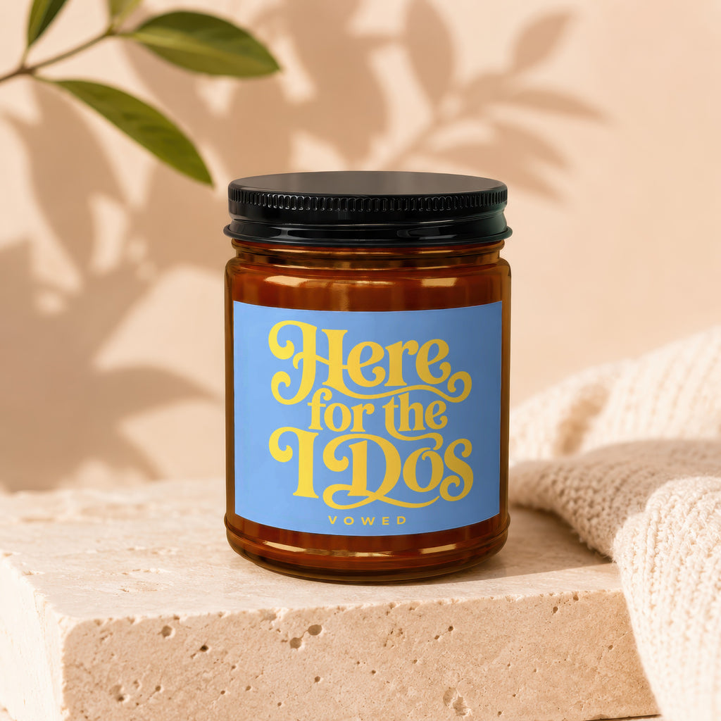 Amber jar candle with blue label reading "Here for the I Do's VOWED".