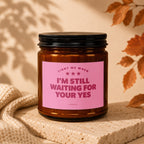 Amber jar candle with pink label reading "LIGHT ME WHEN I'M STILL WAITING FOR YOUR YES".