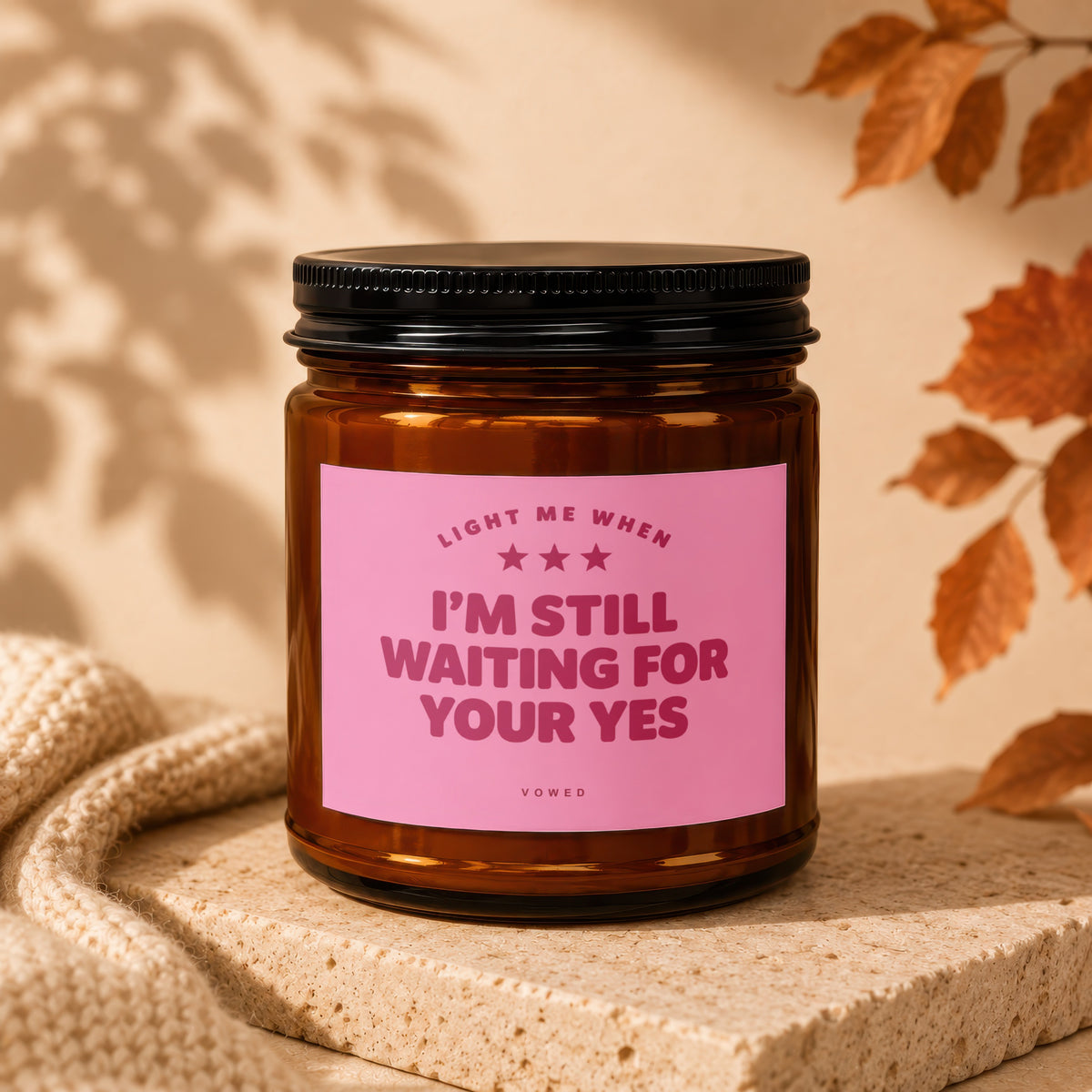 Amber jar candle with pink label reading "LIGHT ME WHEN I'M STILL WAITING FOR YOUR YES".