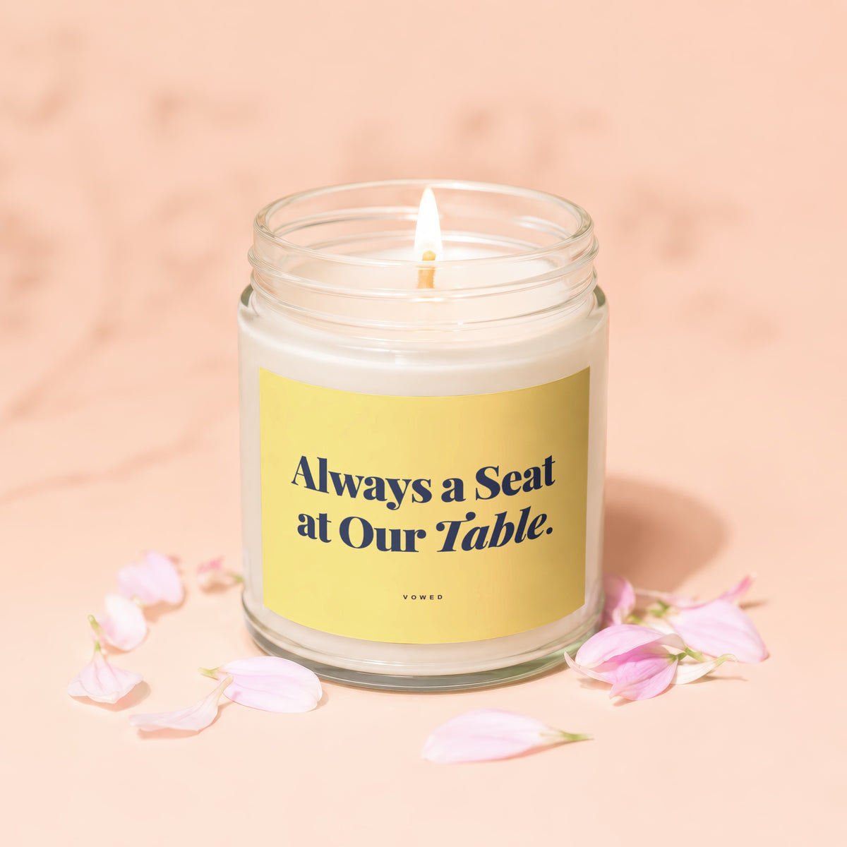 Candle with yellow label reading "Always a Seat at Our Table."