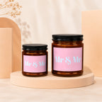 Two amber glass candles with pink labels reading "Mr & Mr".