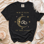 Black t-shirt with "Written in the Stars" text and celestial moon and rings graphic.
