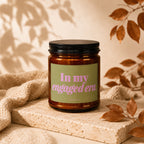 Amber candle with black lid, green label reading "In my engaged era. VOWED."
