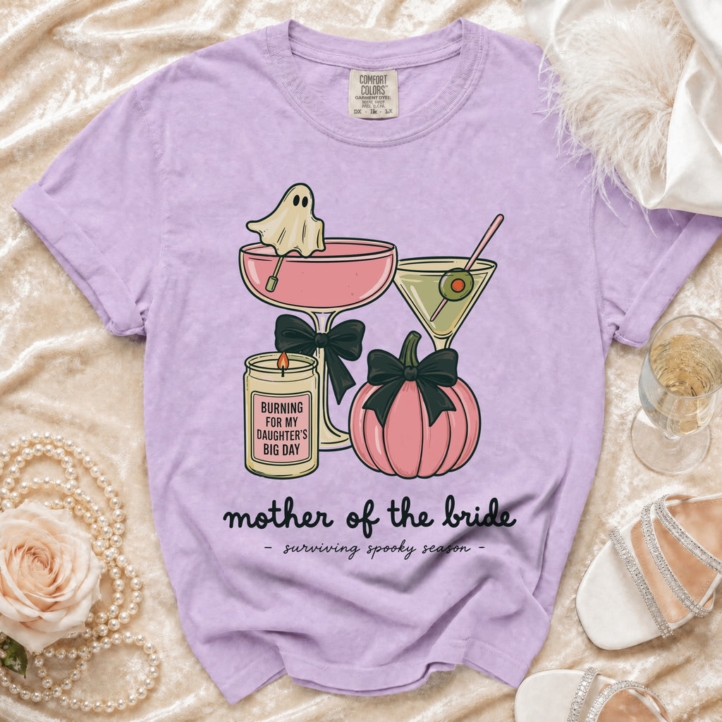 Purple t-shirt with ghost, cocktails, pumpkin, candle, and text "mother of the bride - surviving spooky season".