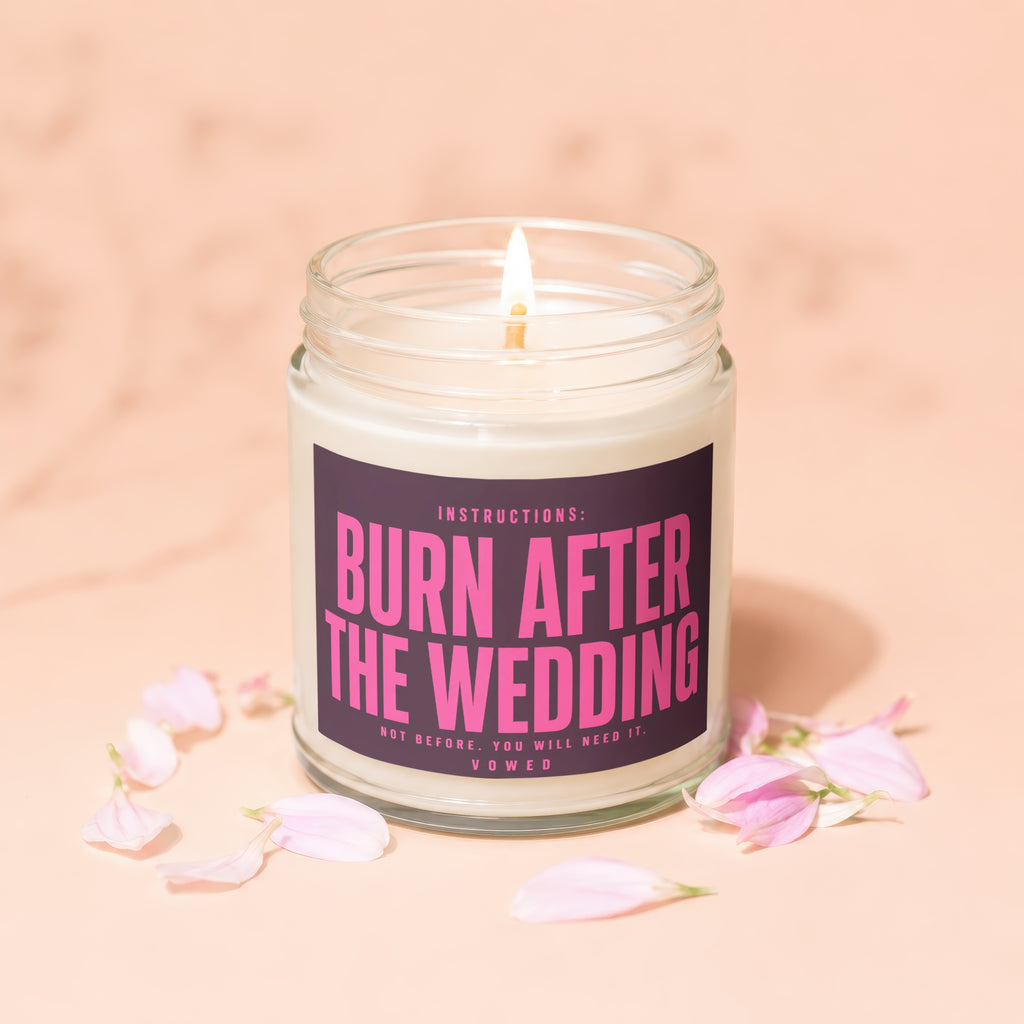 Candle with "Burn After The Wedding" text and scattered pink flower petals.