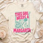 Cream t-shirt with pink text "THIS GIRL NEEDS A MARGARITA" and margarita graphic.