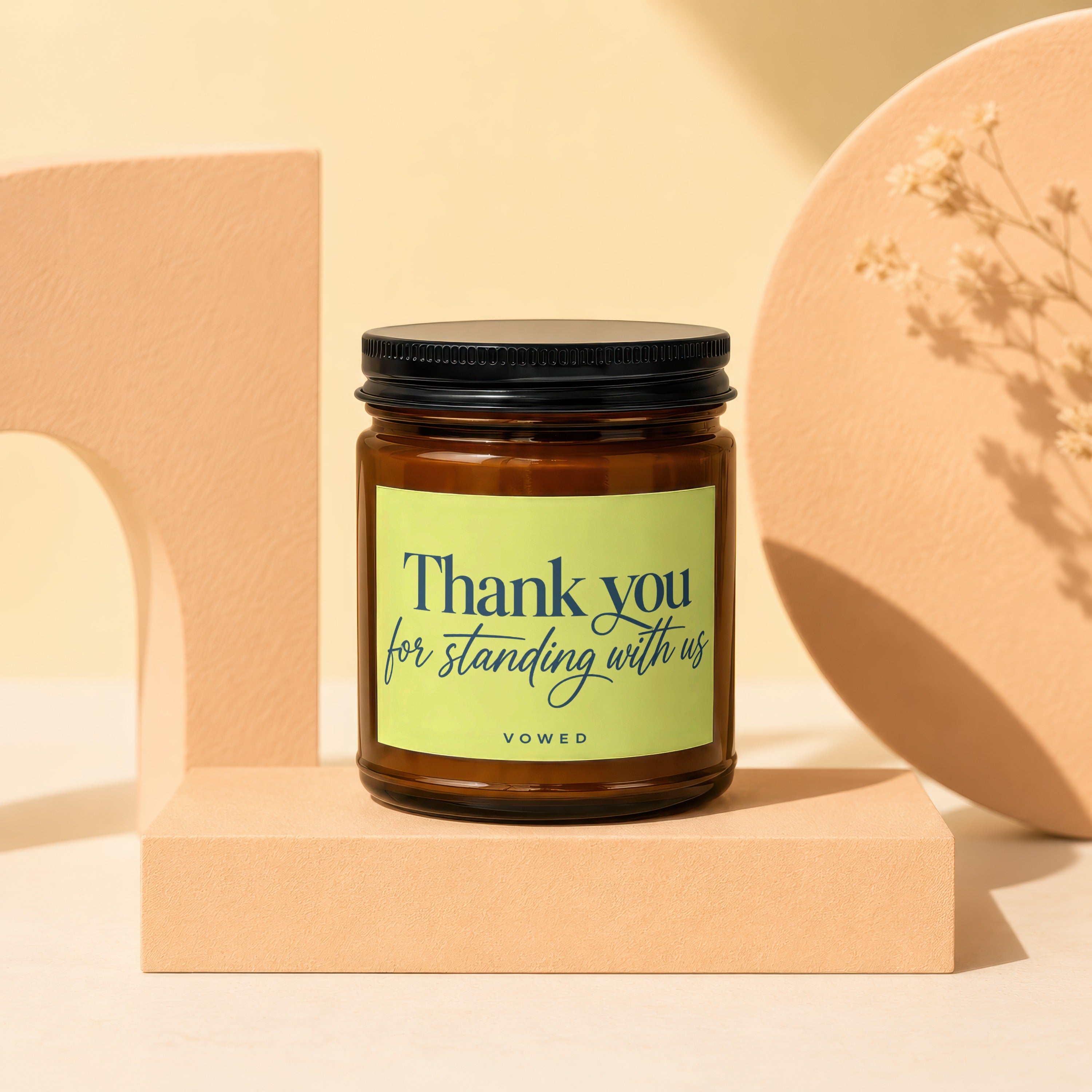 Amber jar candle with a light green label reading "Thank you for standing with us, VOWED."