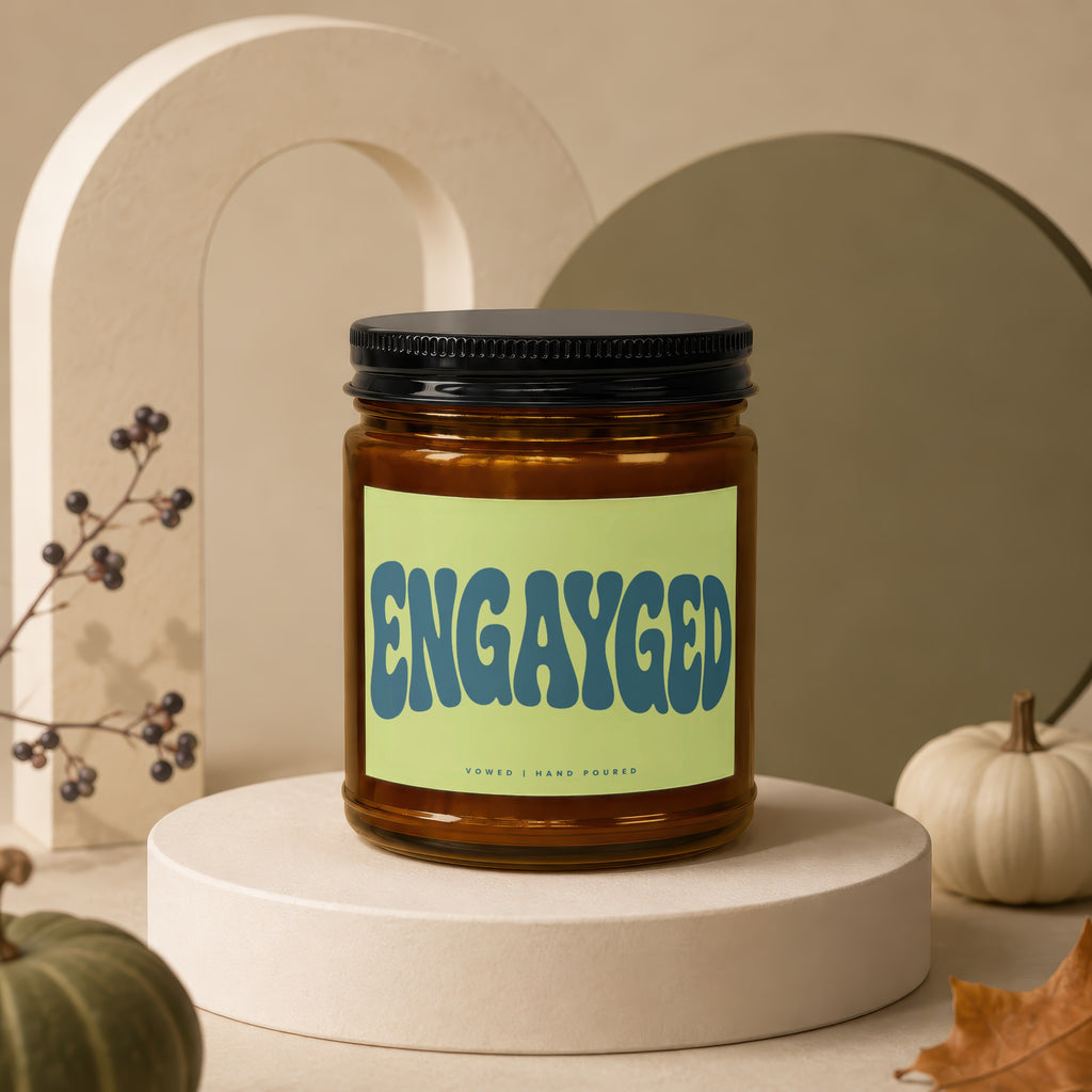 Amber jar candle with "ENGAYGED" text and "VOWED | HAND POURED" details.