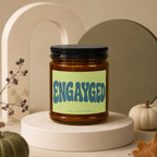 Amber jar candle with "ENGAYGED" text and "VOWED | HAND POURED" details.