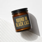 Amber jar candle with black lid, label reads "SWORN: BOUND IN BLACK LACE AND NOT LOOKING FOR A WAY OUT VOWED".