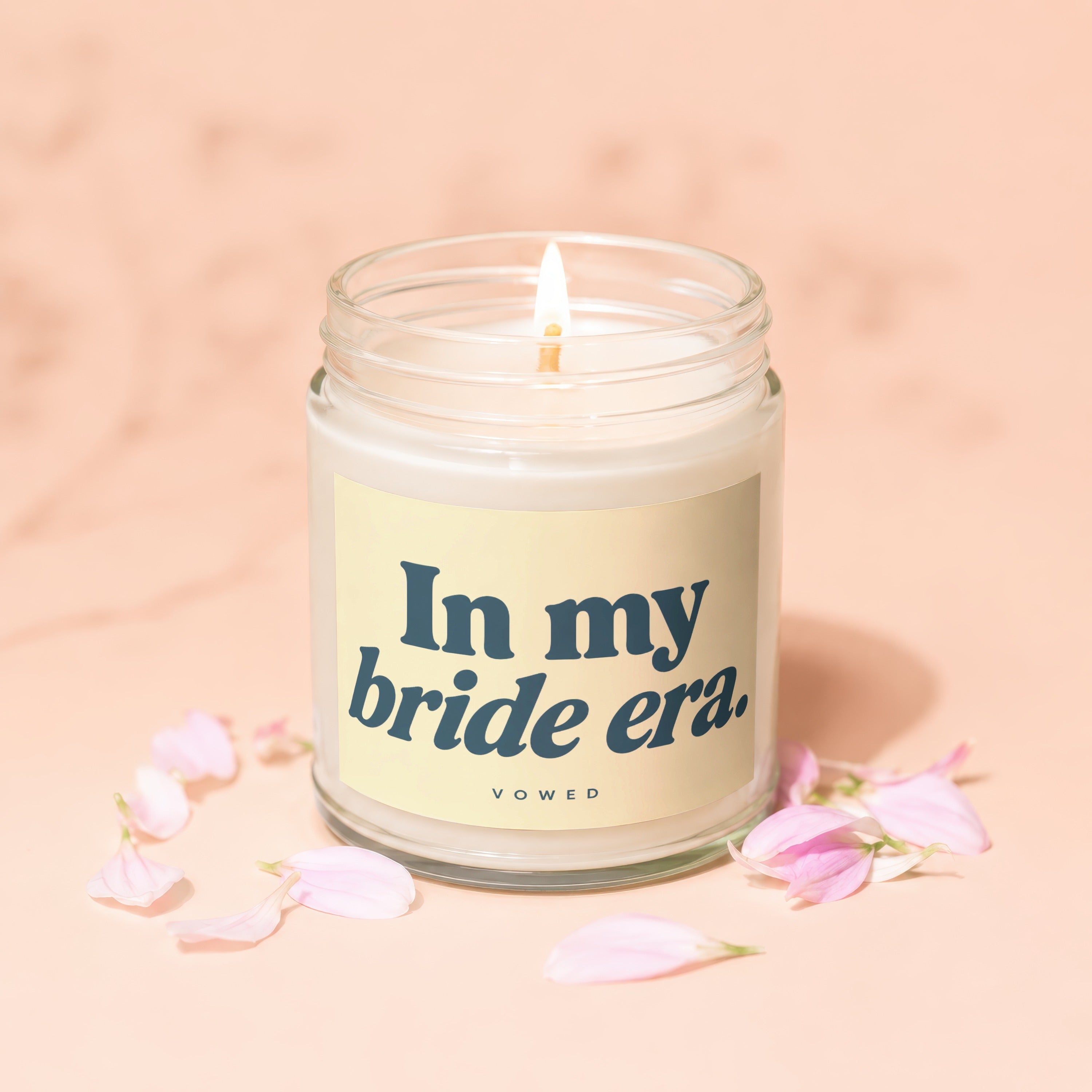 Candle with "In my bride era." text and petals on a peach background.