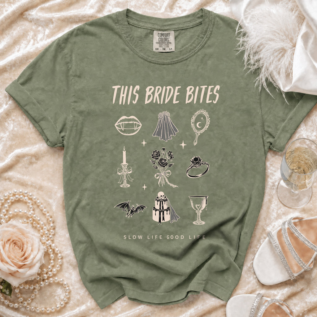 Green t-shirt with vampire fangs, wedding veil, and skull cake graphic. "THIS BRIDE BITES" text.