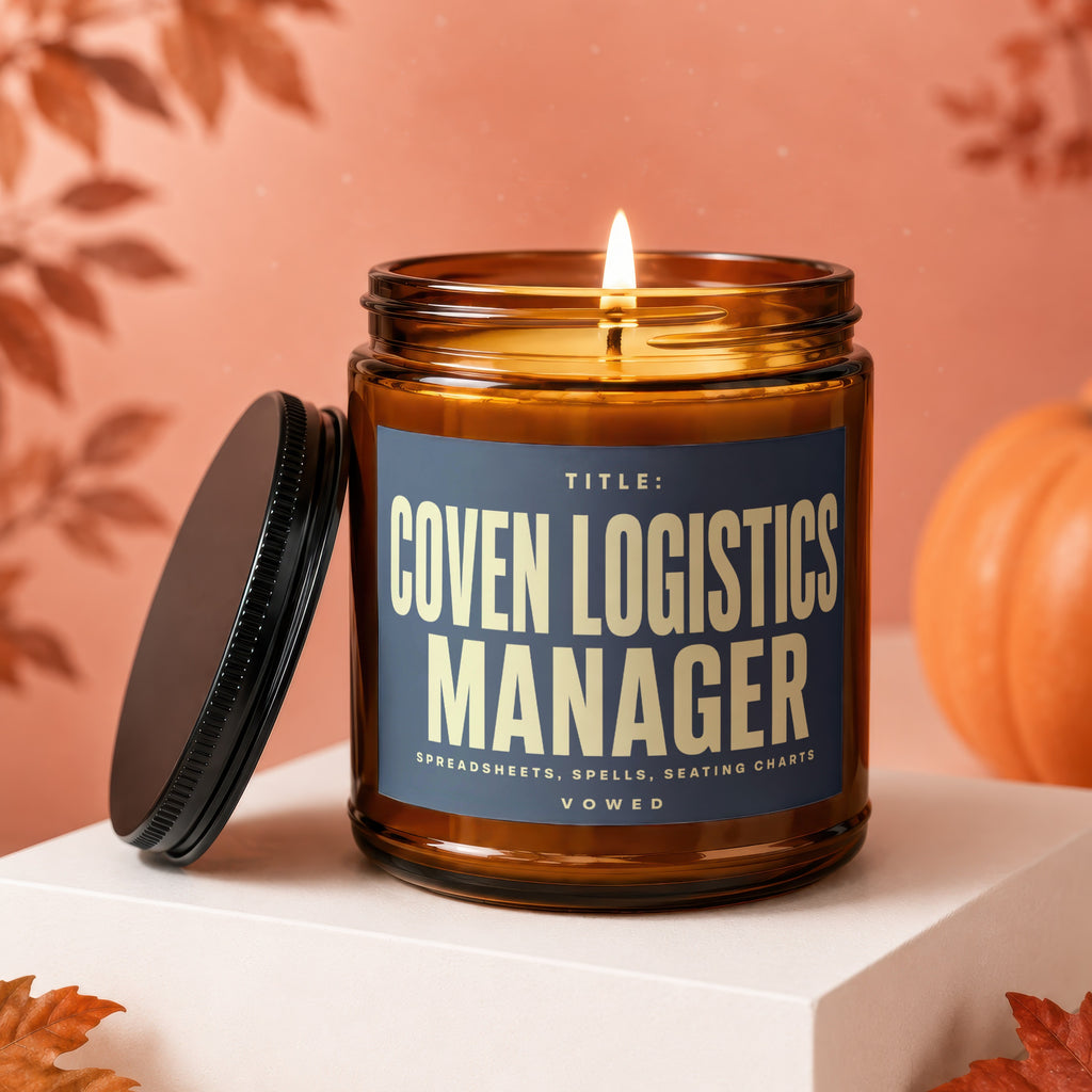 Amber jar candle with "COVEN LOGISTICS MANAGER" text, lit wick, and pumpkin.