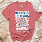 Comfort Colors t-shirt with "Reckless in Texas" text, disco ball, cowboy boots, and hat.