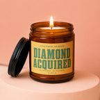Amber jar candle with lit wick and lid off, reads "Achievement Unlocked Diamond Acquired".