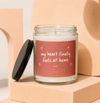 Glass candle with red label reading "my heart finally feels at home."