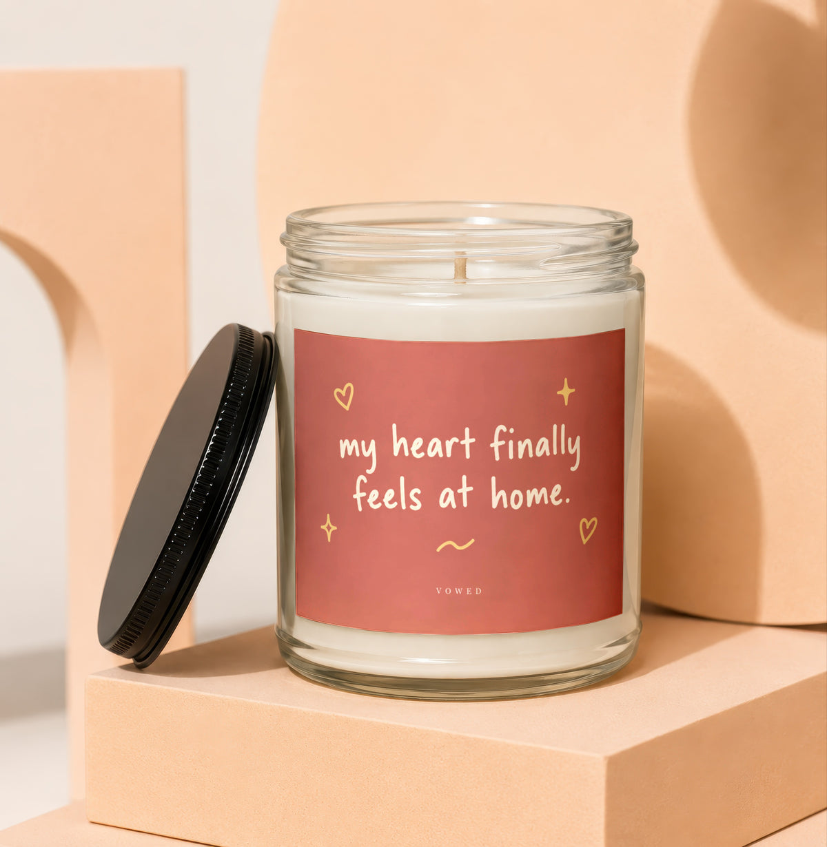 Glass candle with red label reading "my heart finally feels at home."