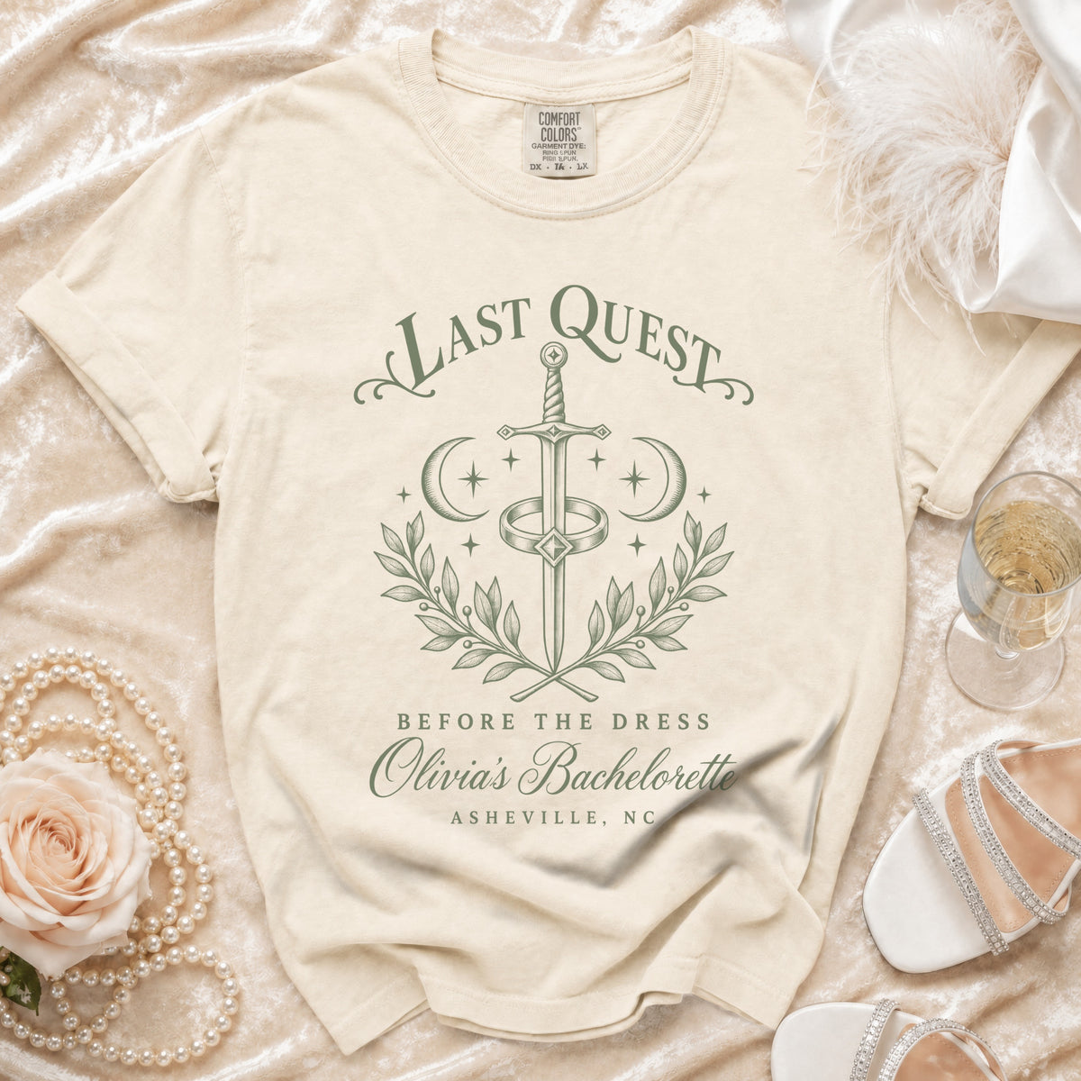 Cream t-shirt featuring green text reading Last Quest Before the Dress, Olivia’s Bachelorette, Asheville, NC.