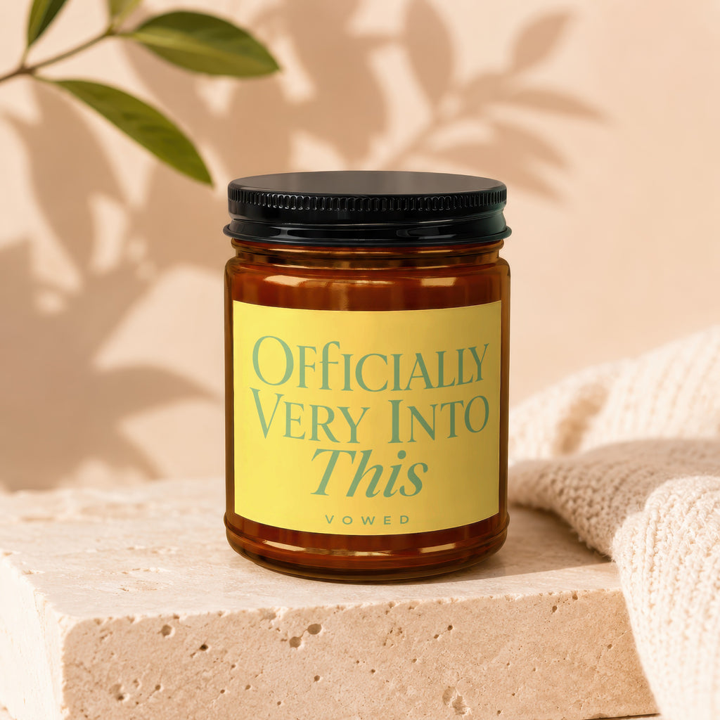 Amber jar candle with yellow label reading "Officially Very Into This".