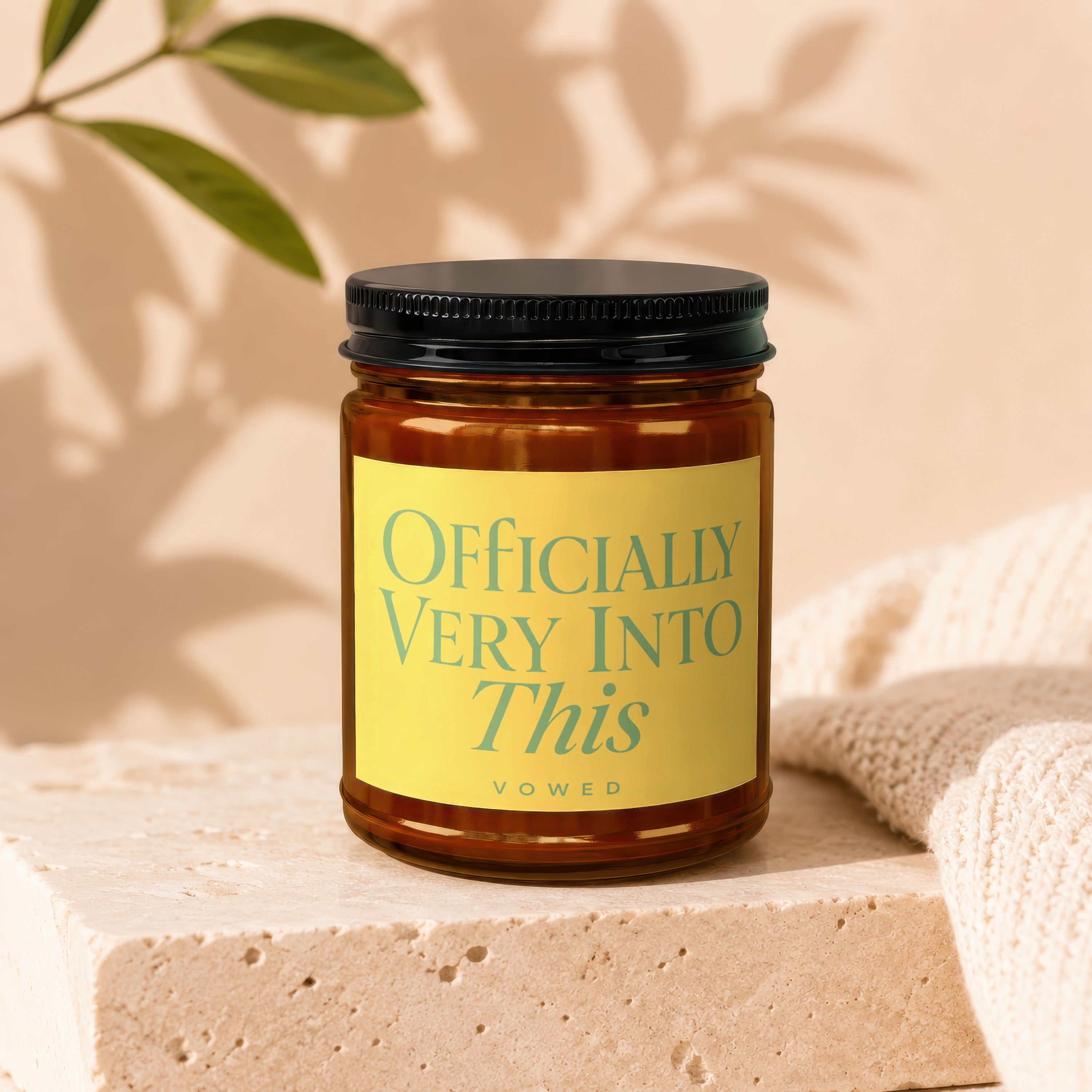 Amber jar candle with yellow label reading "Officially Very Into This".