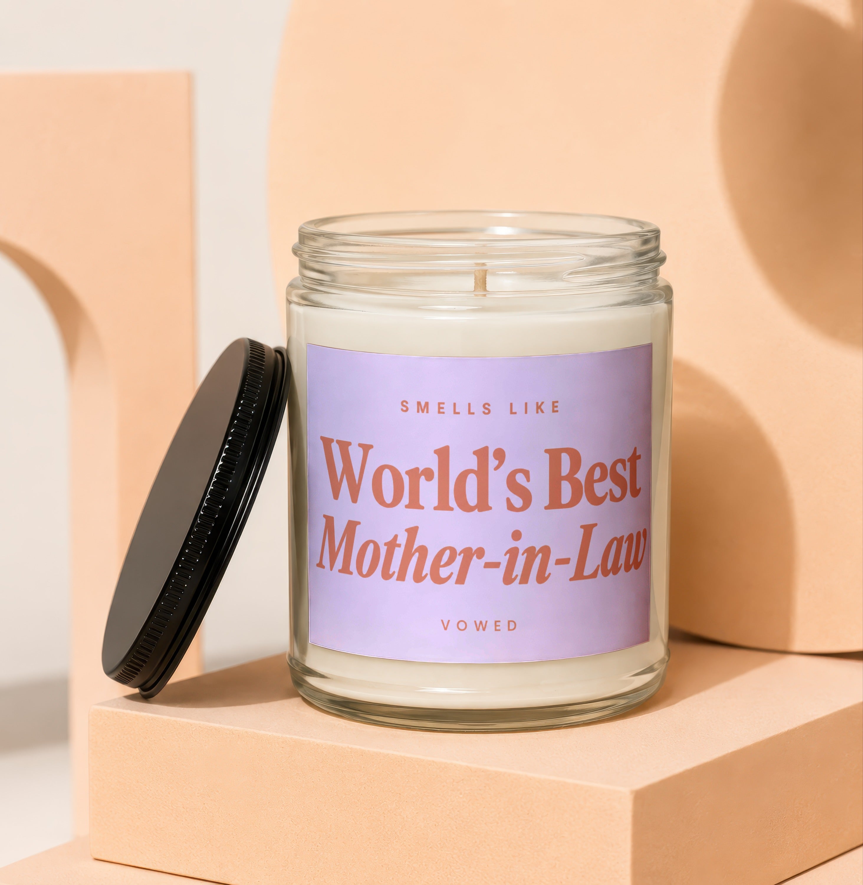 Glass candle with lavender label that reads "Sells Like World's Best Mother-in-Law."