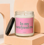 Glass candle with pink label reading "In my newlywed era."