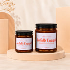 Two amber glass candles with white labels reading "Joyfully Engaged".