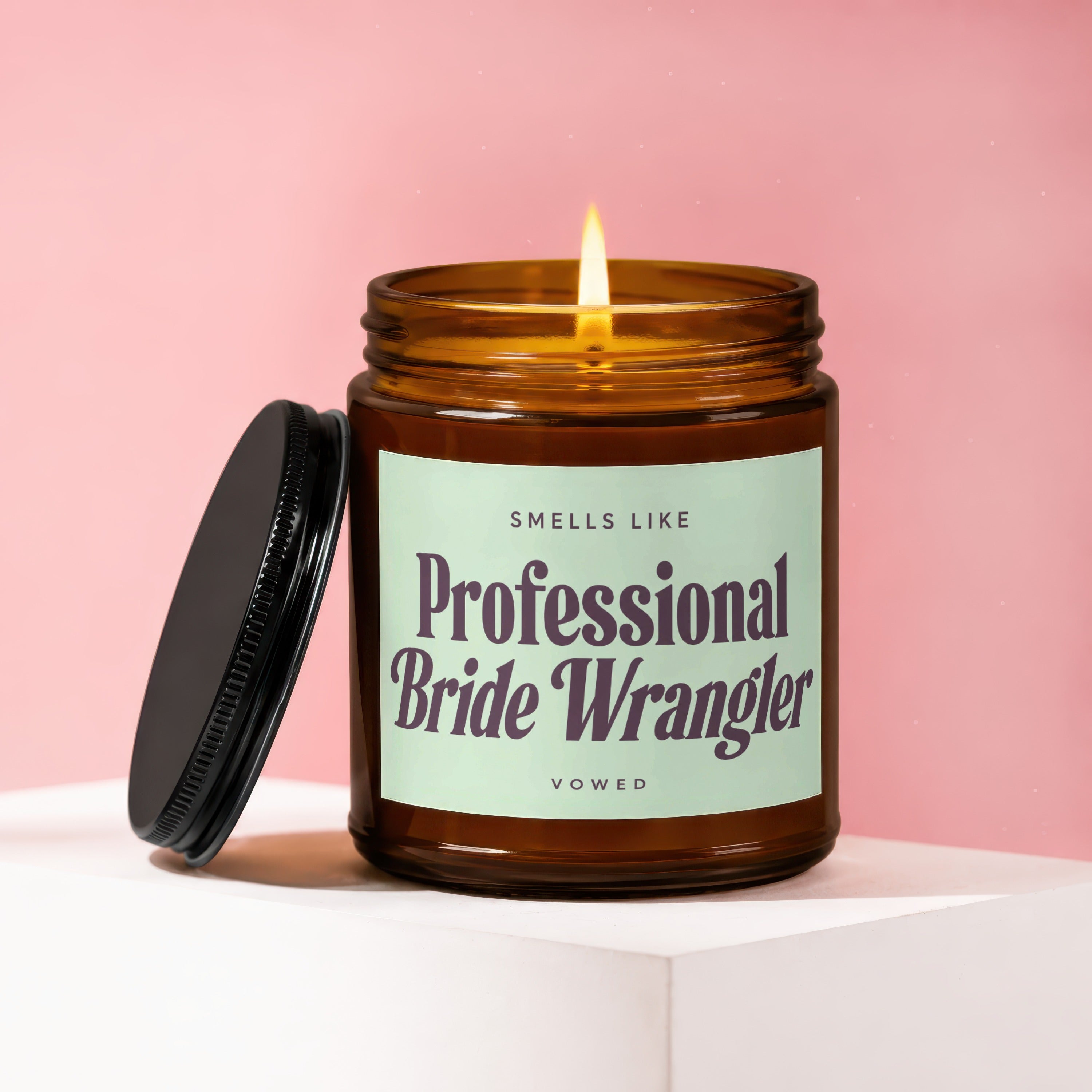 Amber jar candle with lid off, lit flame, and "Smells like Professional Bride Wrangler" text.