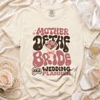 Tan t-shirt with "Mother of the Bride AKA Wedding Planner" text and bouquet graphic.