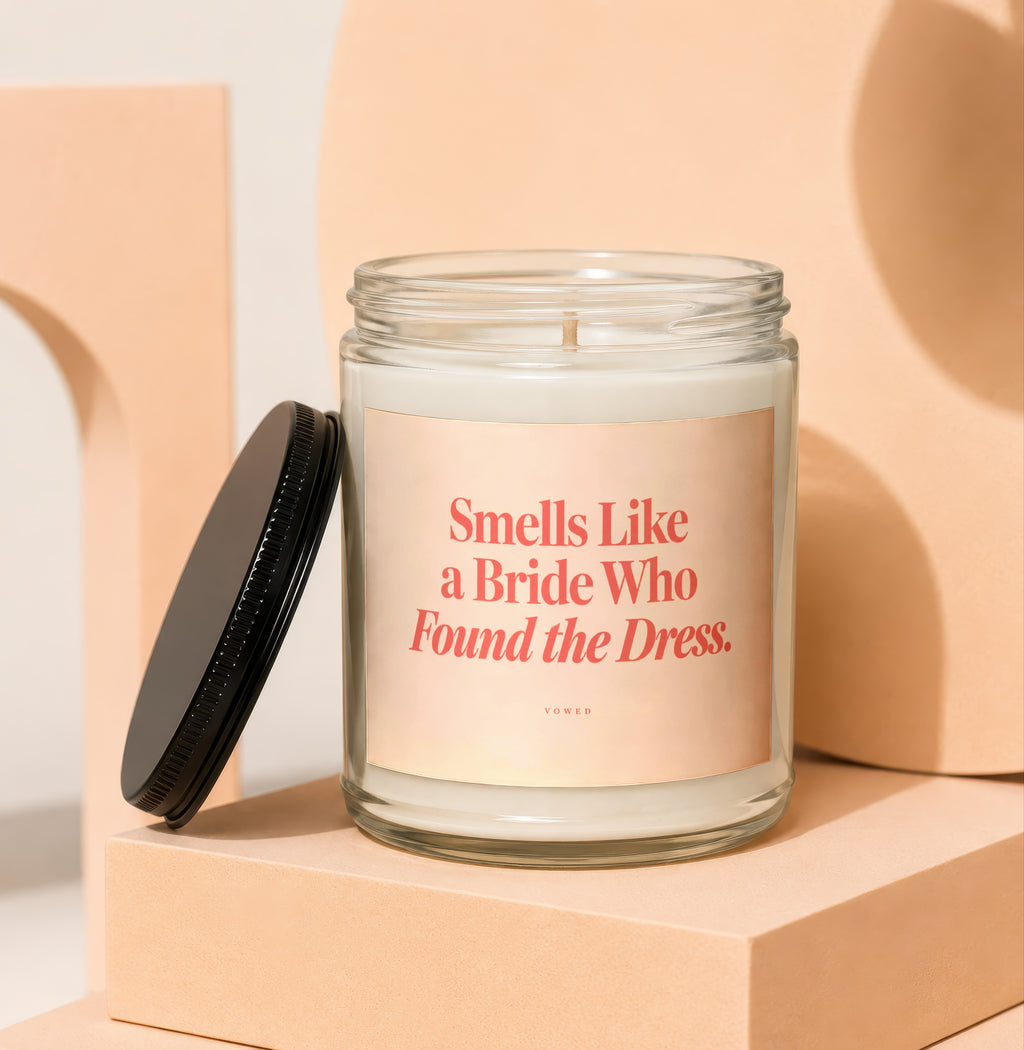 Glass candle with label reading "Smells Like a Bride Who Found the Dress."