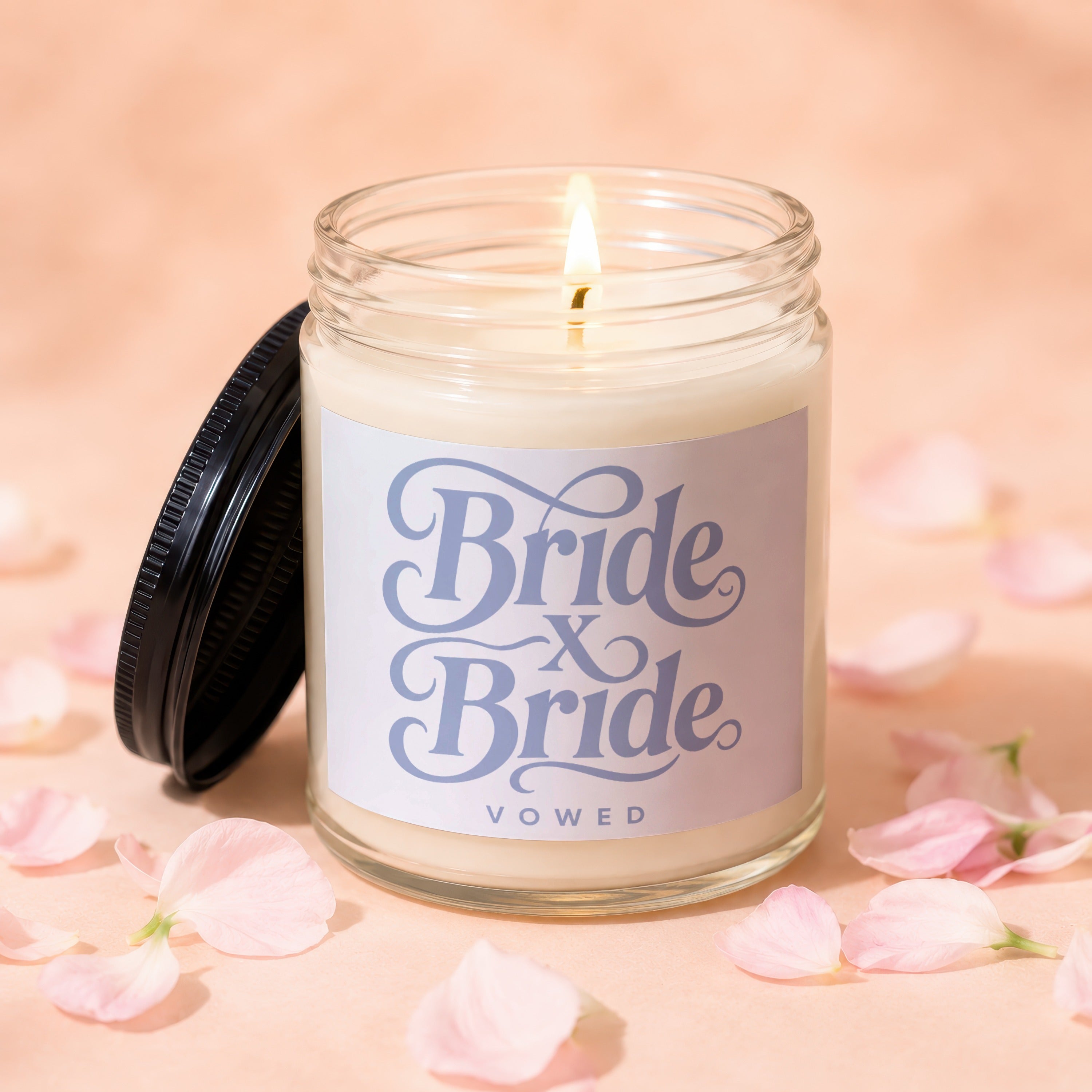 Glass candle with lit wick and lid ajar, reading "Bride x Bride Vowed."