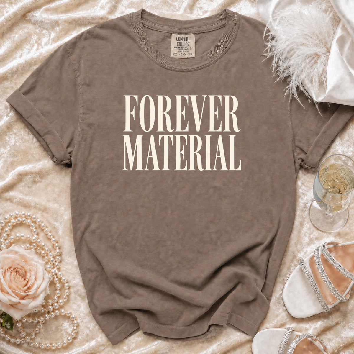 Brown t-shirt with "FOREVER MATERIAL" in white serif font, Comfort Colors tag.