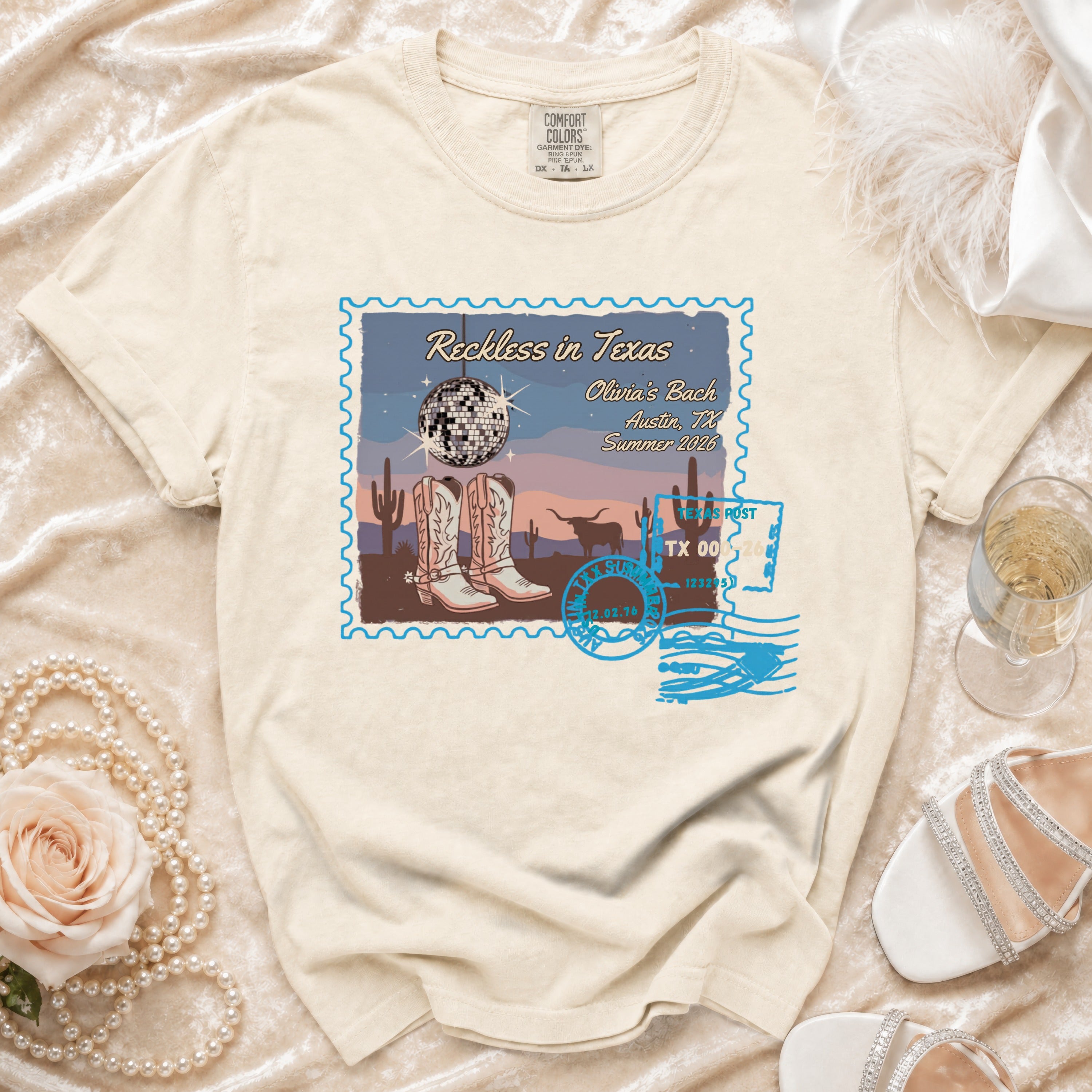 T-shirt with "Reckless in Texas" design, disco ball, boots, and postcard elements.