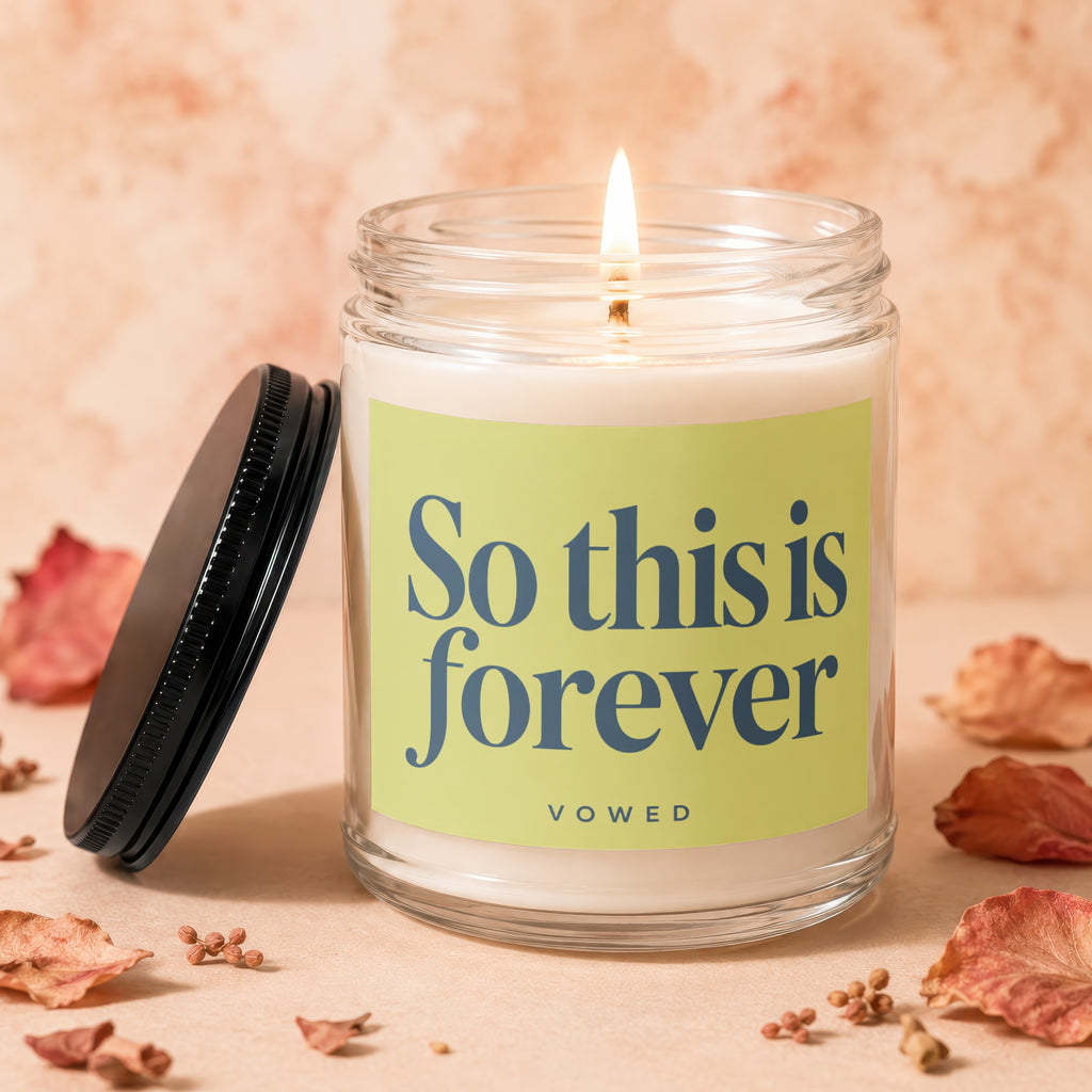 Jar candle with lit wick, lid off, and "So this is forever vowed" label.