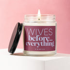 Glass jar candle with lit wick and lid removed, says "Wives before... everything VOWED".