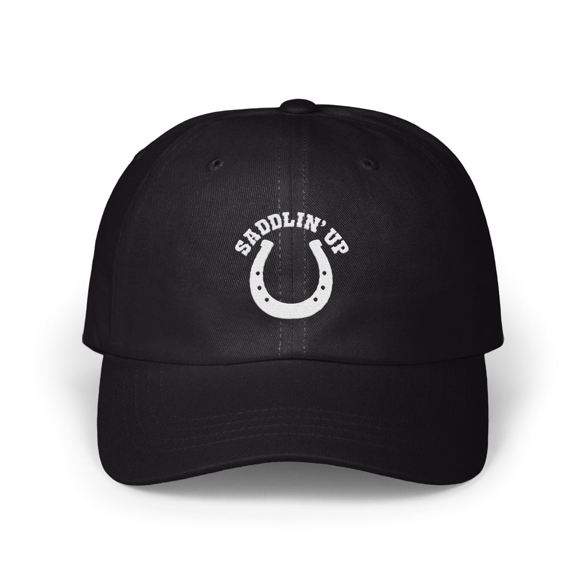 Black dad hat featuring a white embroidered horseshoe and the text SADDLIN' UP on the front panel.