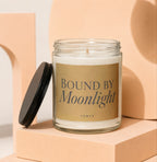 Glass jar candle with "BOUND BY Moonlight" and "VOWED" text on gold label.