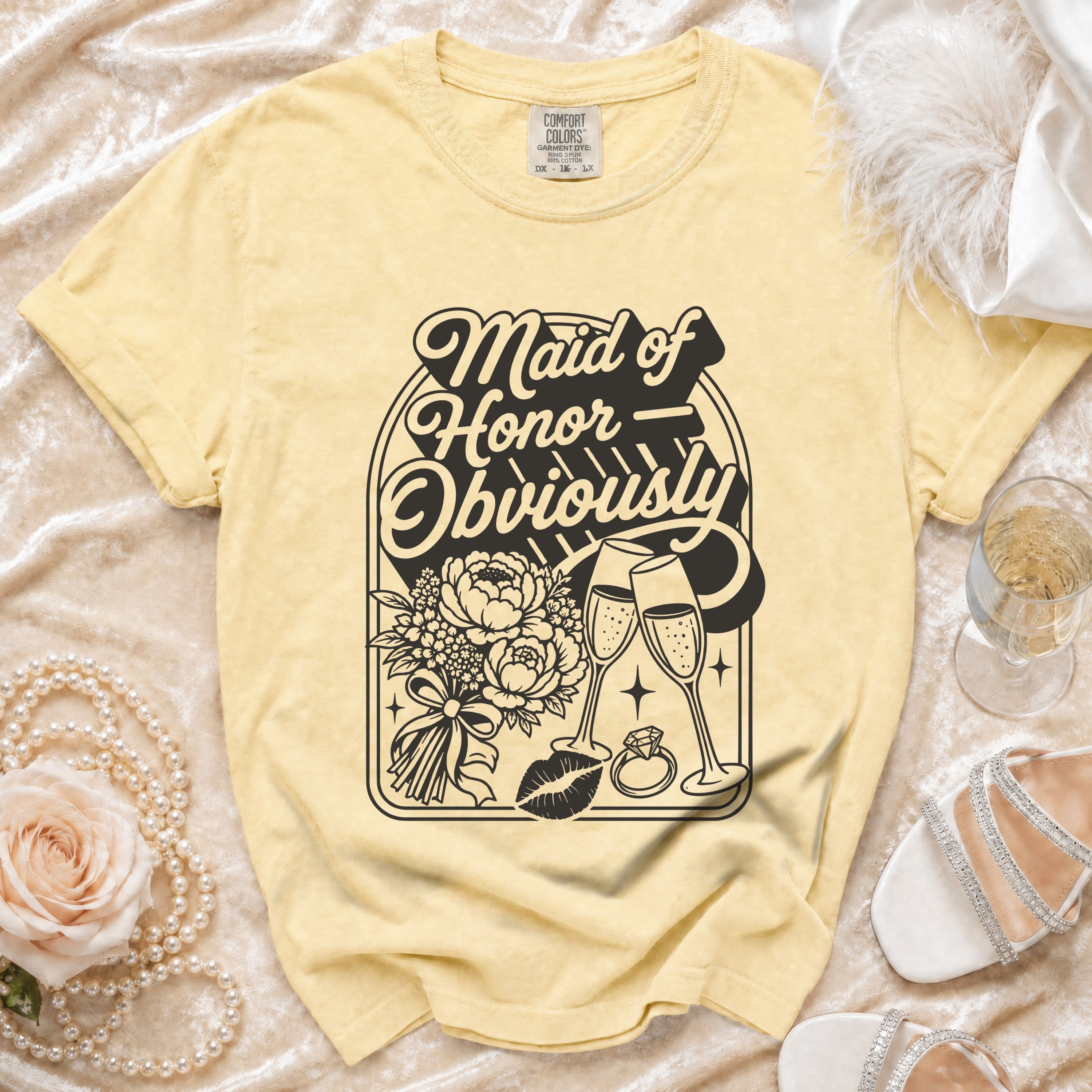 Yellow t-shirt with "Maid of Honor Obviously" graphic featuring flowers, champagne, kiss, and ring.